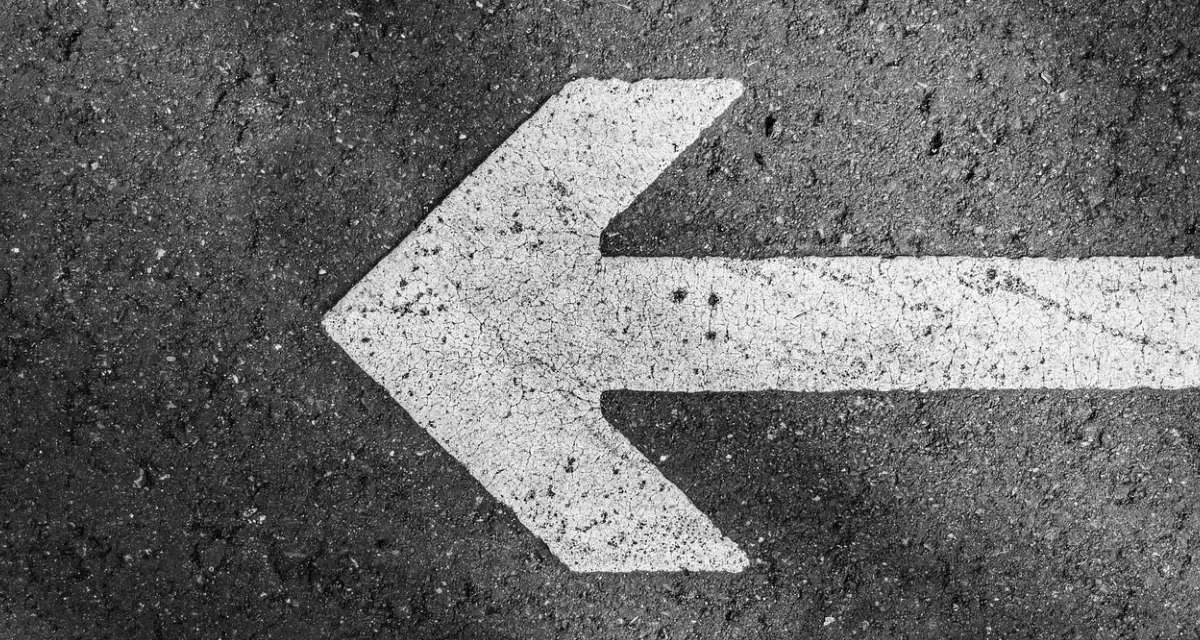 Ein Pfeil auf einer Straße, der nach links zeigt. 