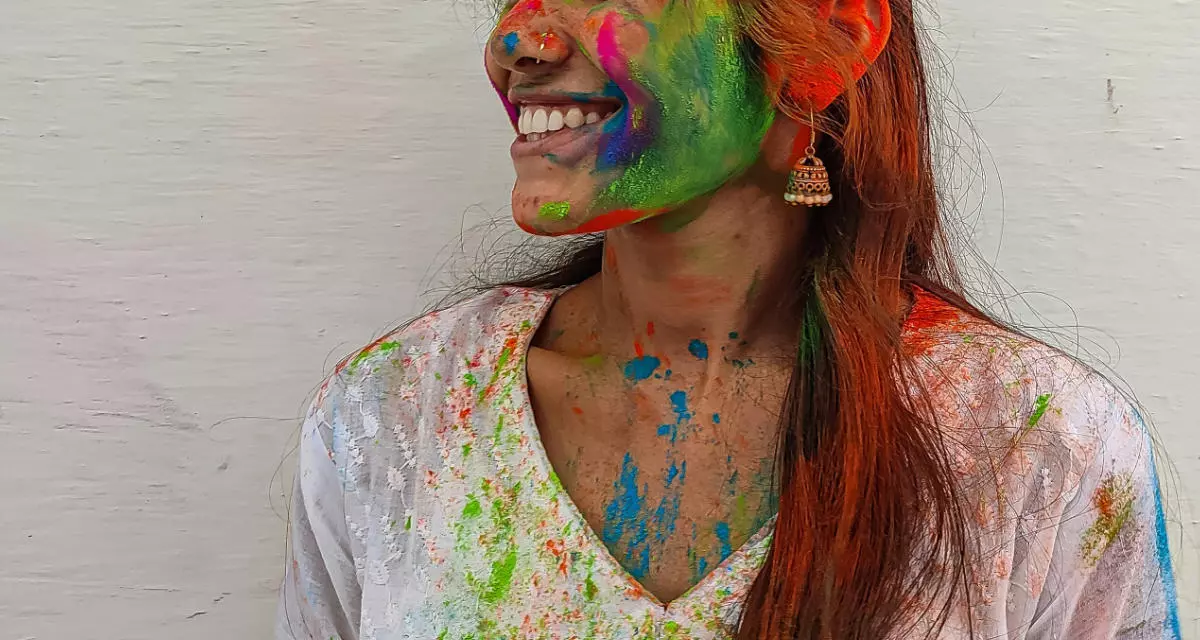 Eine mit bunter Farbe bemalte Frau lacht