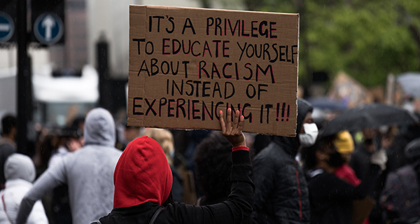 "Es ist ein Privileg, sich über Rassismus zu informieren, anstatt ihn zu erleben." Plakat auf einer Demonstration. Foto: Unsplash / James Eades. 